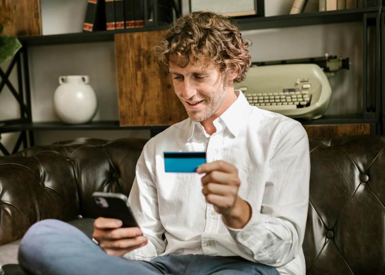 Payment Gateway Man sat down holding credit card and phone